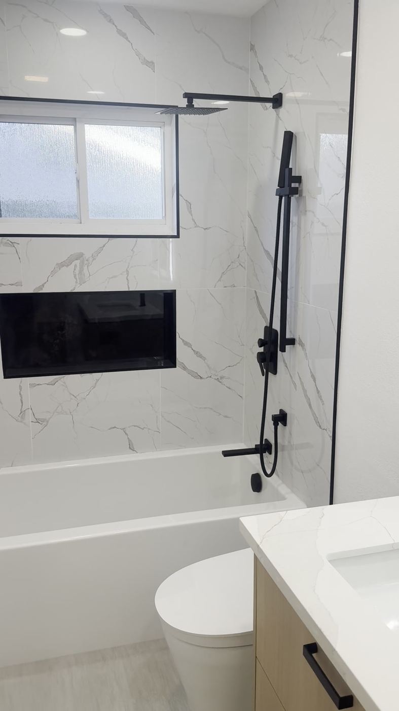 Soaking tub with matte black fixtures and marble tile
